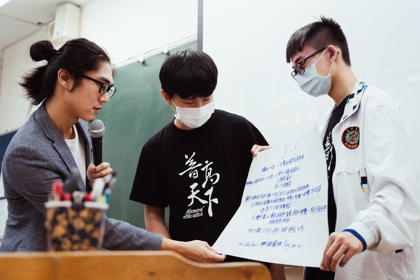 鄉育講師與高中生在課堂展示成果海報、推動教育公益