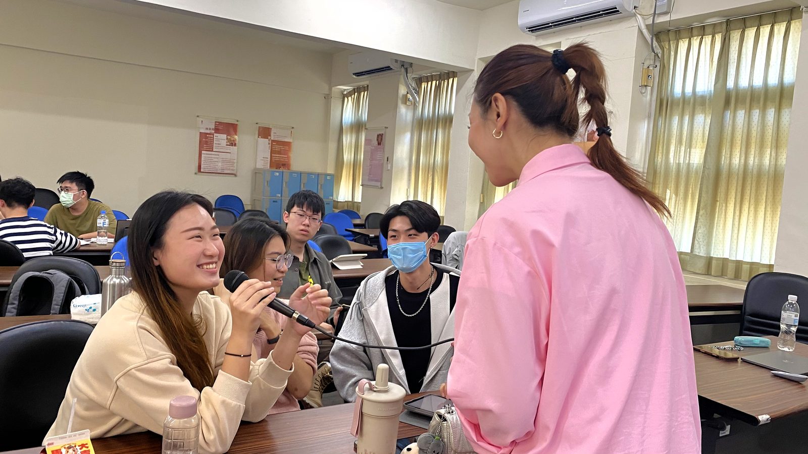 講師走進課堂與學生面對面交流，學生拿著麥克風笑著回應