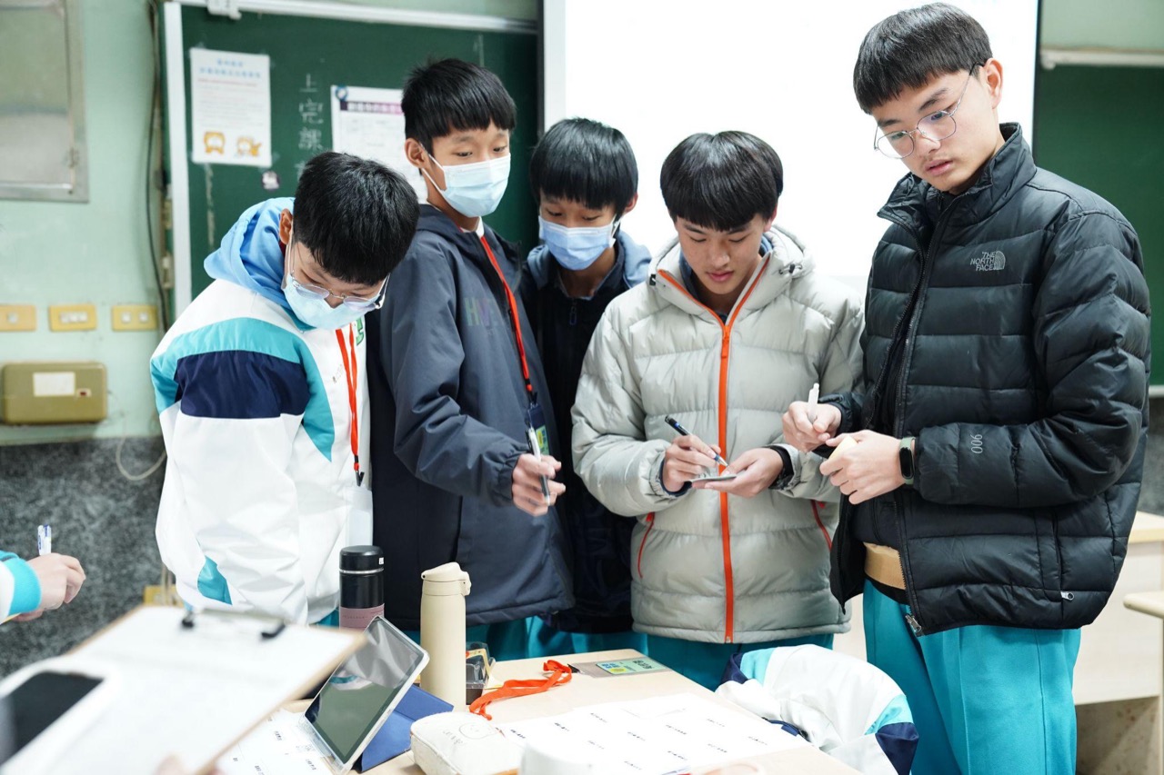 學生圍著平板與手機，一起討論與動手操作