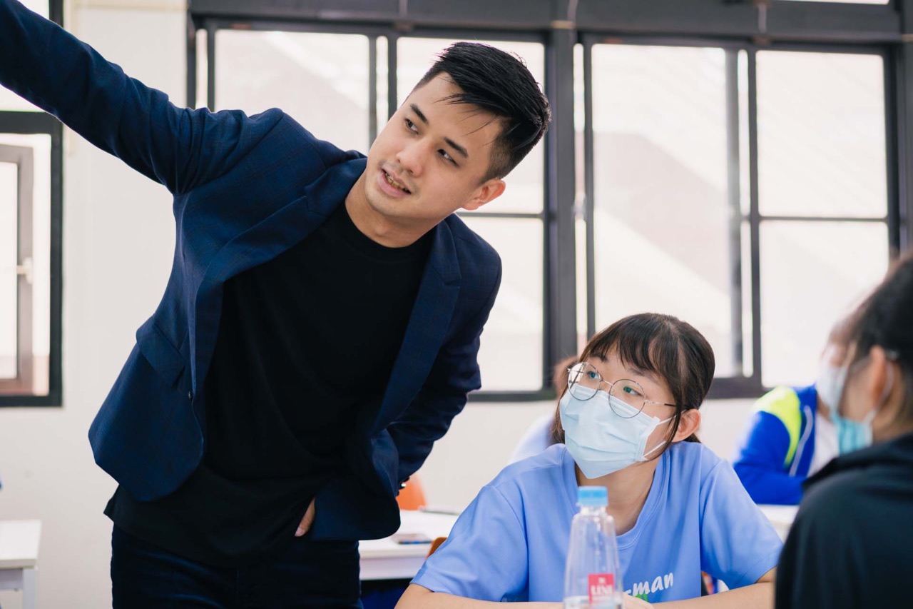 鄉育業師俯身與學生一對一討論、近距離陪伴